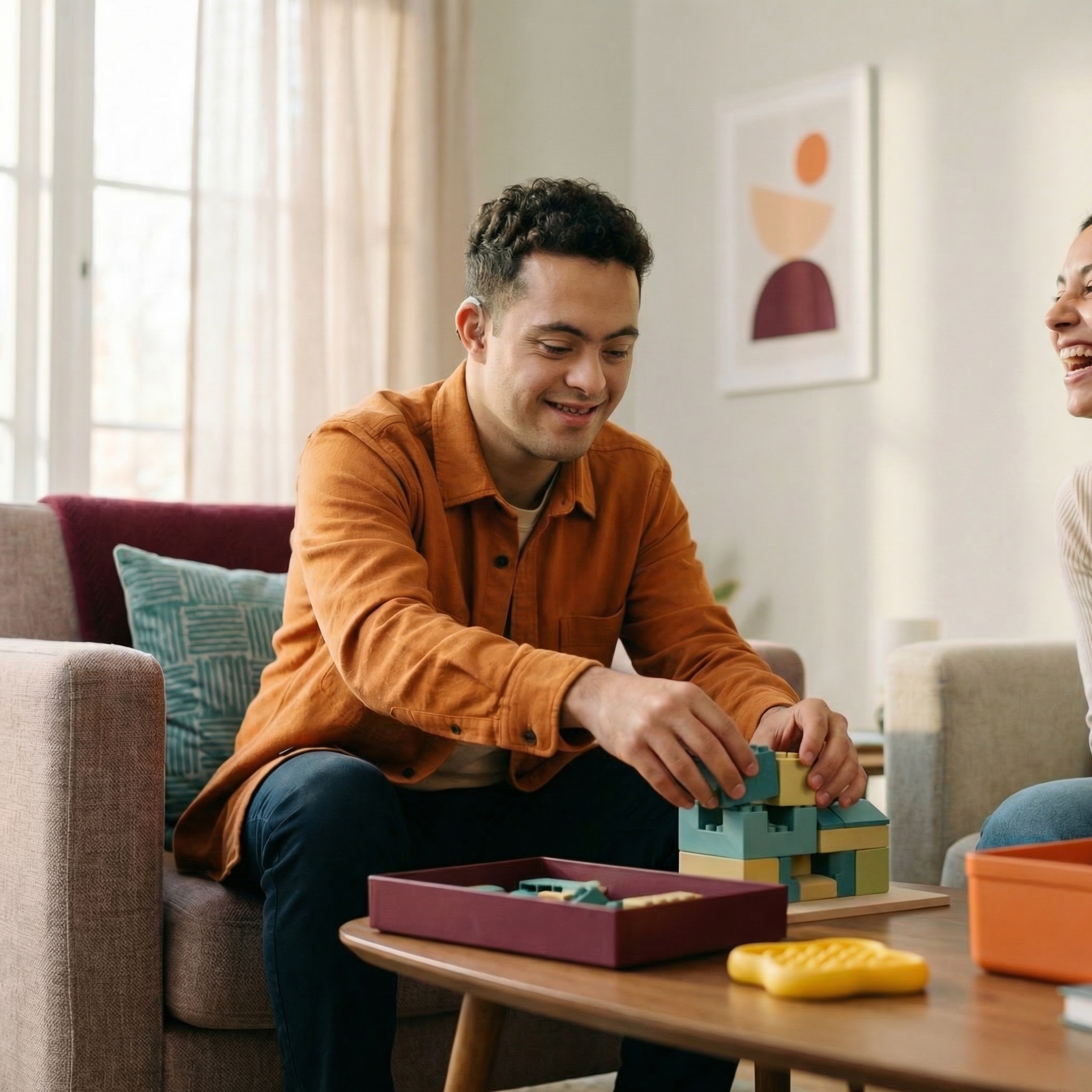 Young man building with colourful blocks on a coffee table with support worker smiling